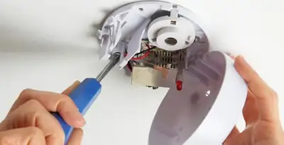 Certified technician wiring smoke detector during installation in Mesa, AZ